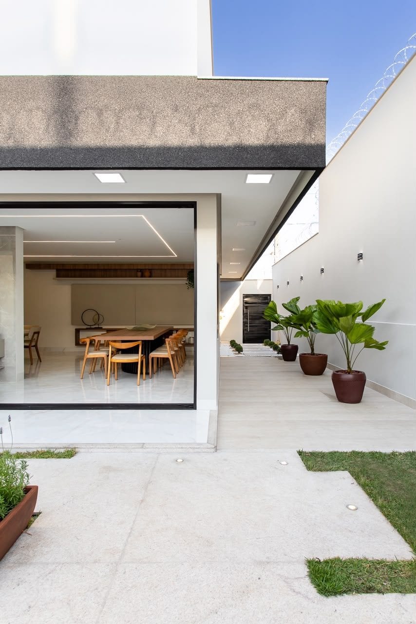 Varanda com piso contínuo, vegetação em vasos e deck integrado ao jardim